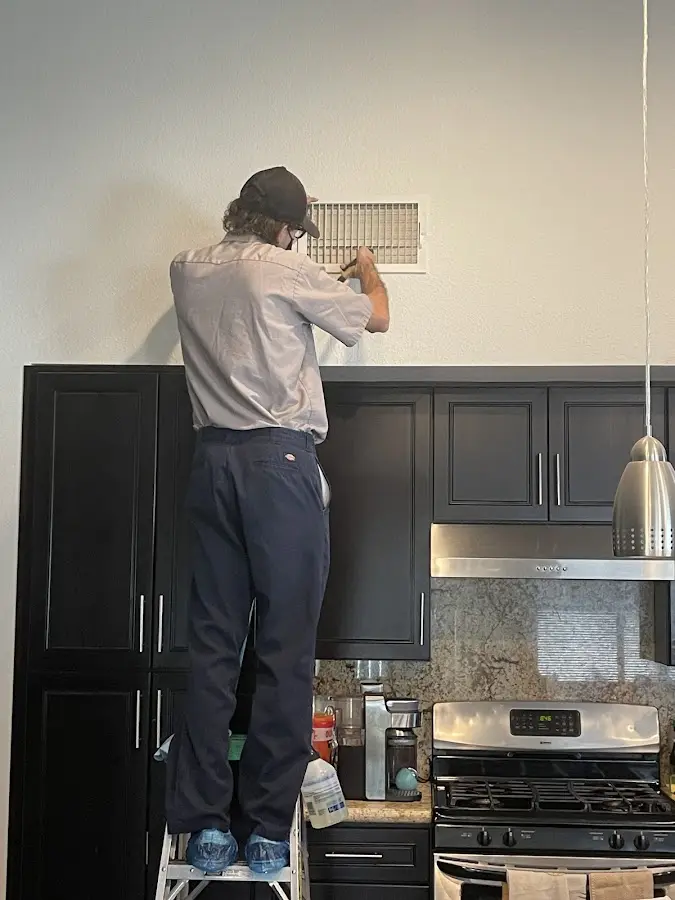 Technician inspecting an air vent during HVAC service in Oatfield